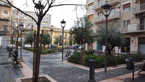 A paved pedestrian area with benches, street lamps, and a tree. - Luxury Catania (Catania)