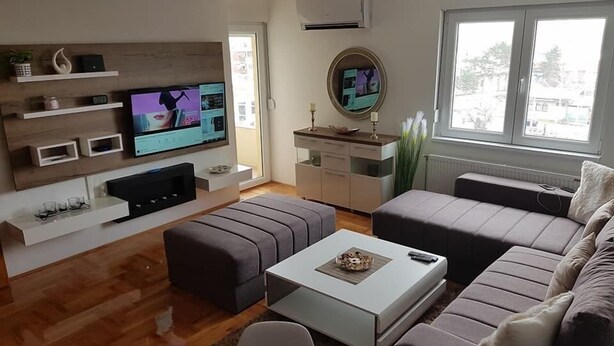 A modern living room with a flat-screen TV, a sofa, a coffee table, and a dining area. - Apartment Panorama Negotin (Negotin)