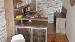 A modern kitchen with wooden cabinets, a stone backsplash, and a dining area with a round table and chairs. - Apartment Panorama Negotin (Negotin)