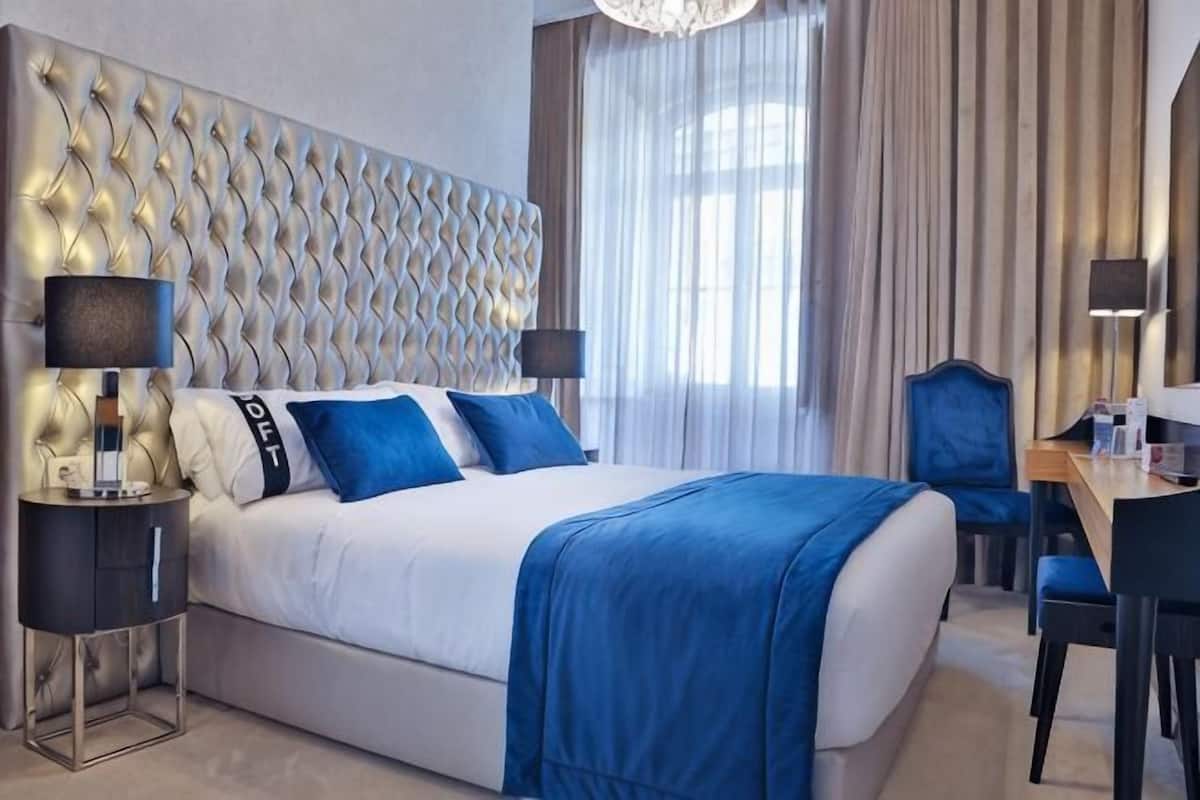 A hotel room with a large bed, two bedside tables, a desk, and a chair.