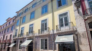 Ein Hotel mit gelber Fassade, mehreren Balkonen und einem gefliesten Eingangsbereich.