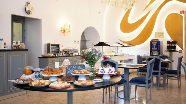 Ein Frühstücksbuffet mit verschiedenen Backwaren und Kuchen, einer Kandelaber und einem modernen Innenarchitekturstil.