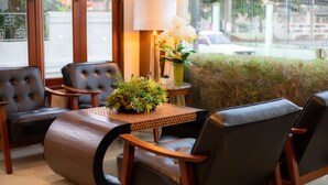 Una sala de estar con sillones de cuero, una mesa de madera y un florero con flores.