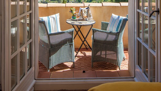 An open balcony with wicker chairs, a small table with drinks, and a city view. - Villa Le Port d'Attache (Cannes)