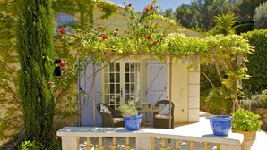 A cozy outdoor seating area with a table and chairs, surrounded by lush greenery and flowering plants. - Villa Le Port d'Attache (Cannes)