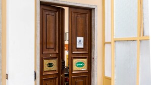 A wooden double door with a plaque, a welcome mat, and a small table with a vase. - Hotel Youri Il Magnifico (Genoa)