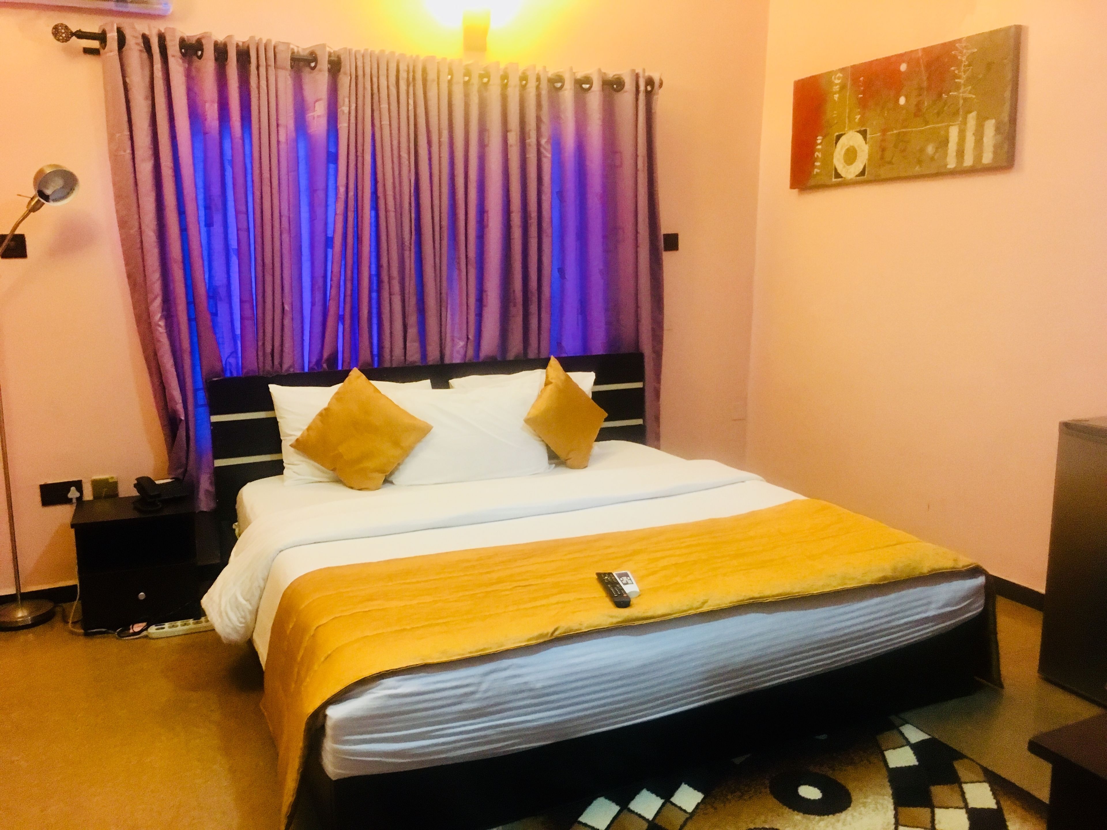 Una habitación de hotel con una cama, una mesita de noche, una lámpara y un cuadro en la pared.