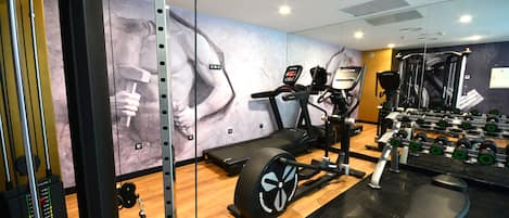 A gym with cardio equipment, weight machines, and a wall with fitness-themed artwork.