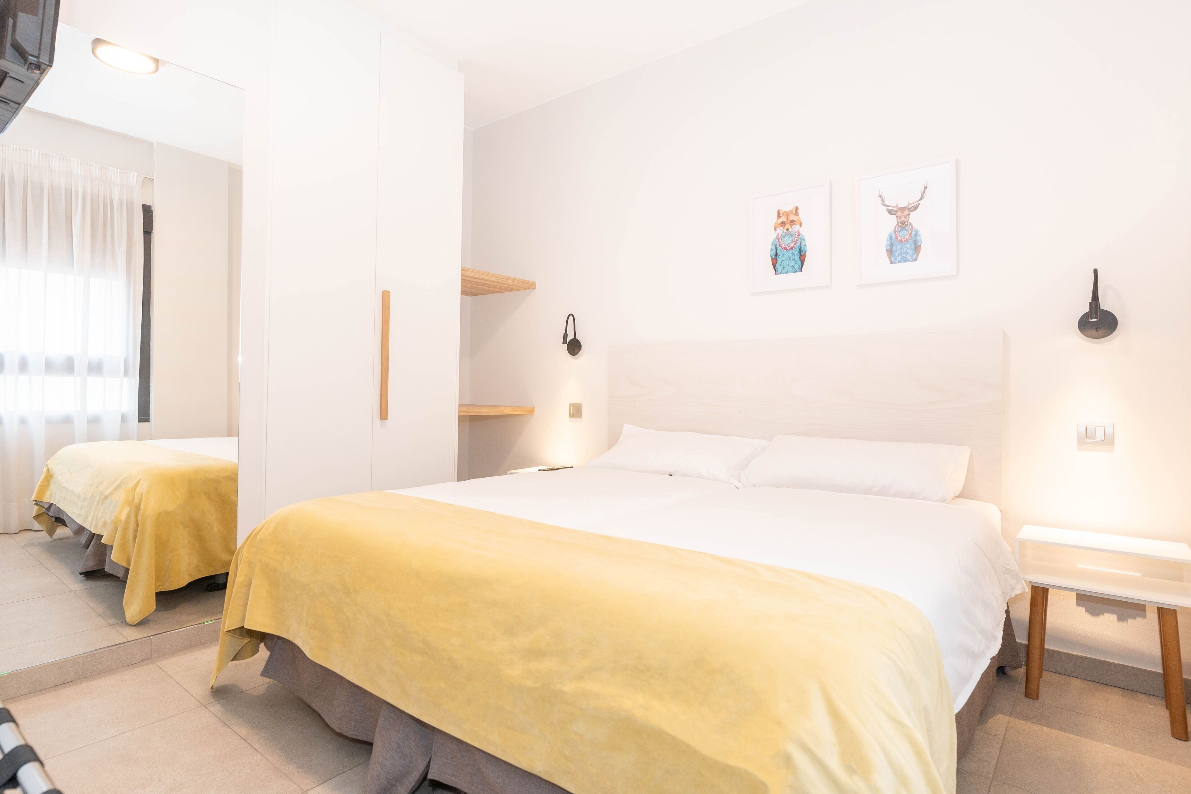 Ein Hotelzimmer mit einem großen Bett, einem Nachttisch, einem Spiegel und Bildern an der Wand.