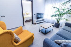 Una sala moderna con sofá, sillón, mesa de centro y televisor.