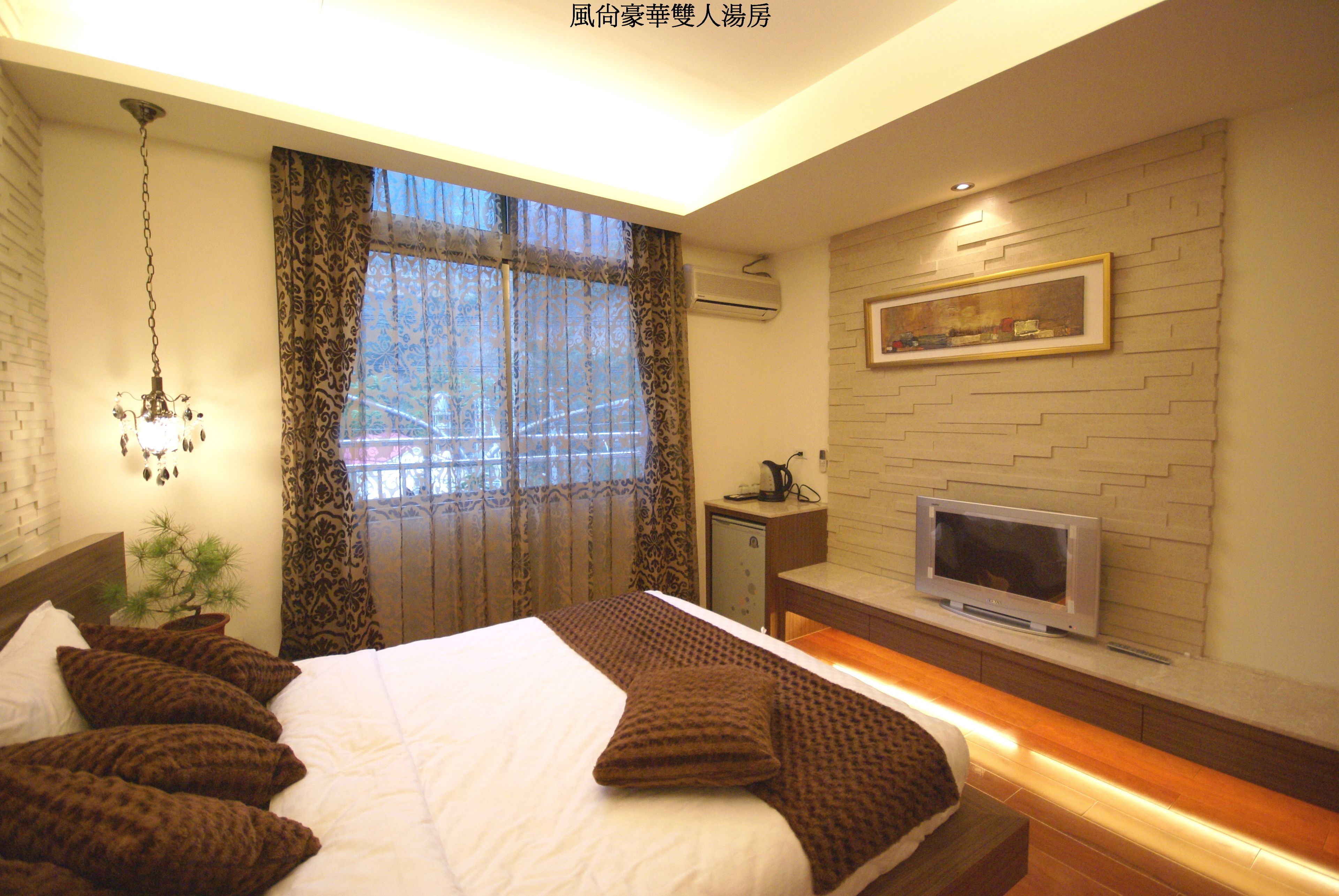 A modern bedroom with a large bed, a TV, and a small desk.