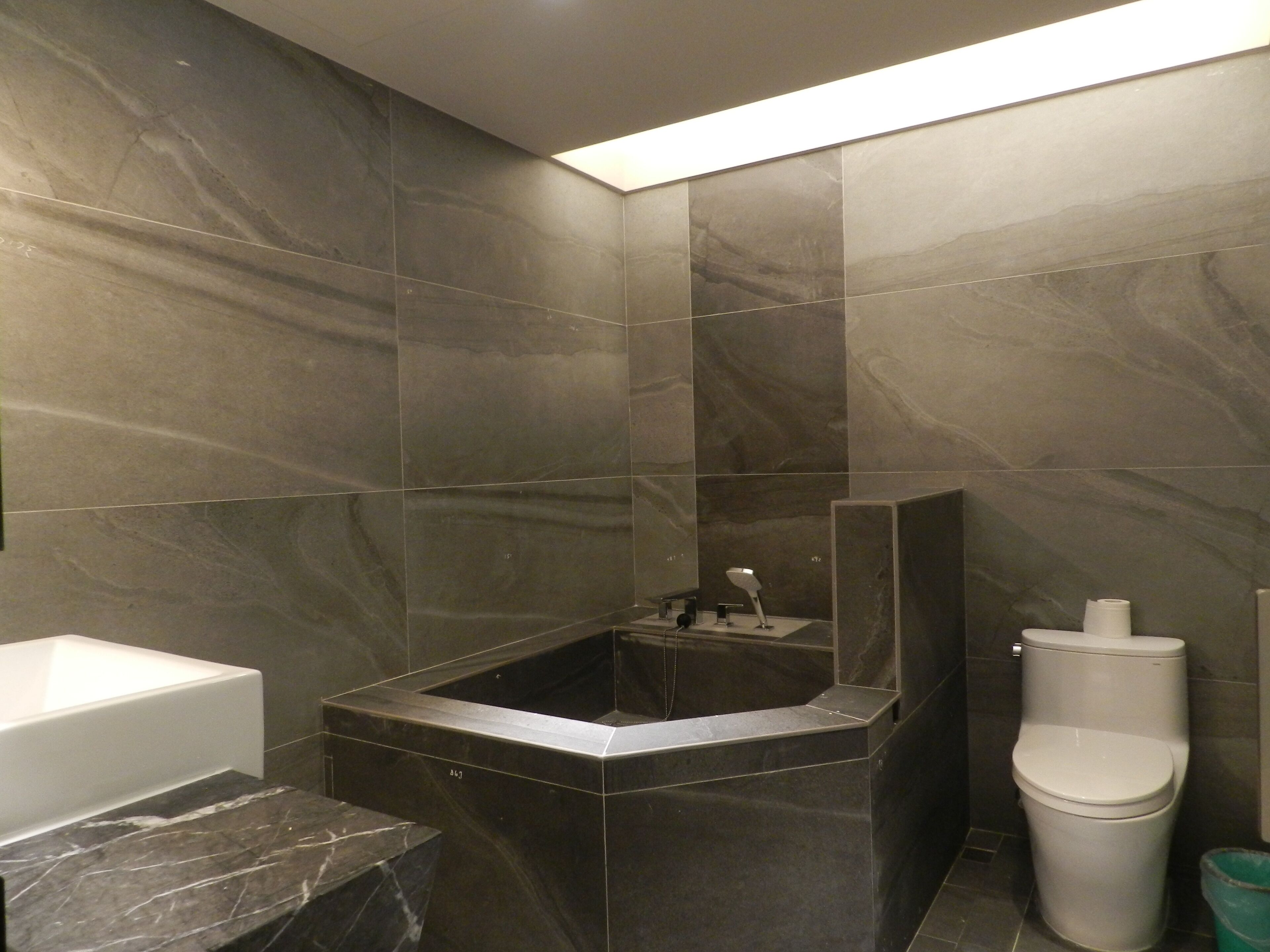 A modern bathroom with a freestanding bathtub, a toilet, and a marble countertop.