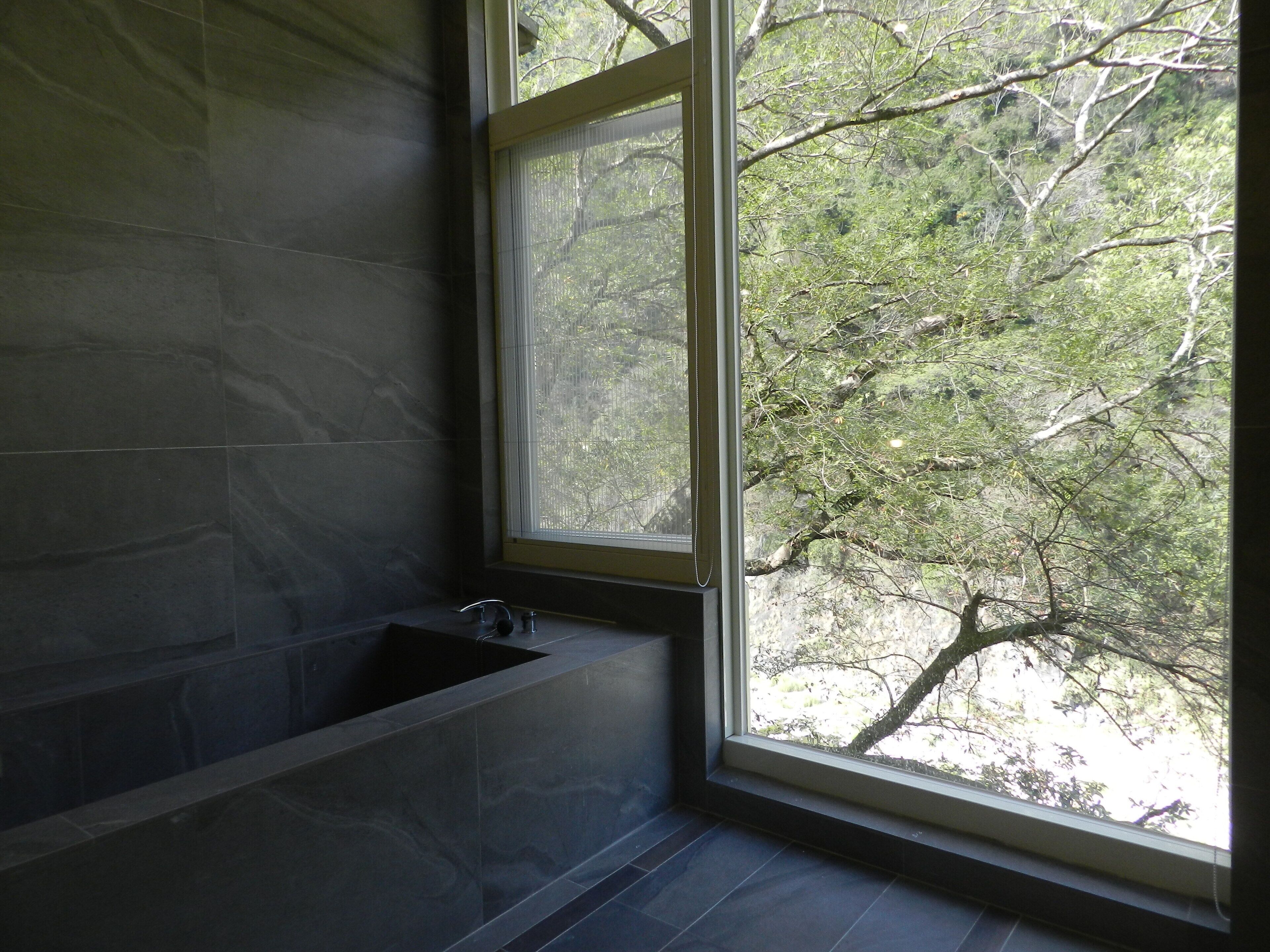 A bathroom with a bathtub, a window, and a view of trees.