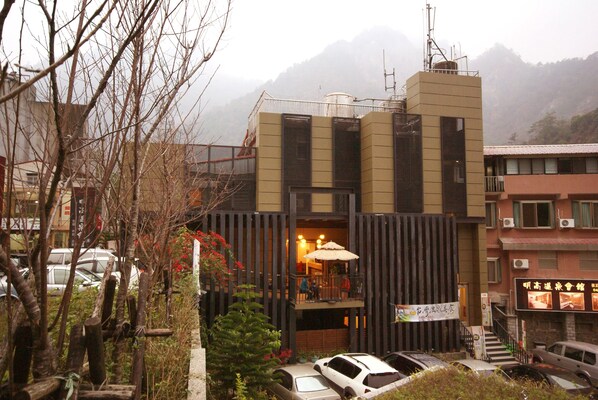 A modern building with a balcony, a staircase, and a signboard.