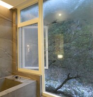 A bathroom with a bathtub, a window, and a view of trees outside.