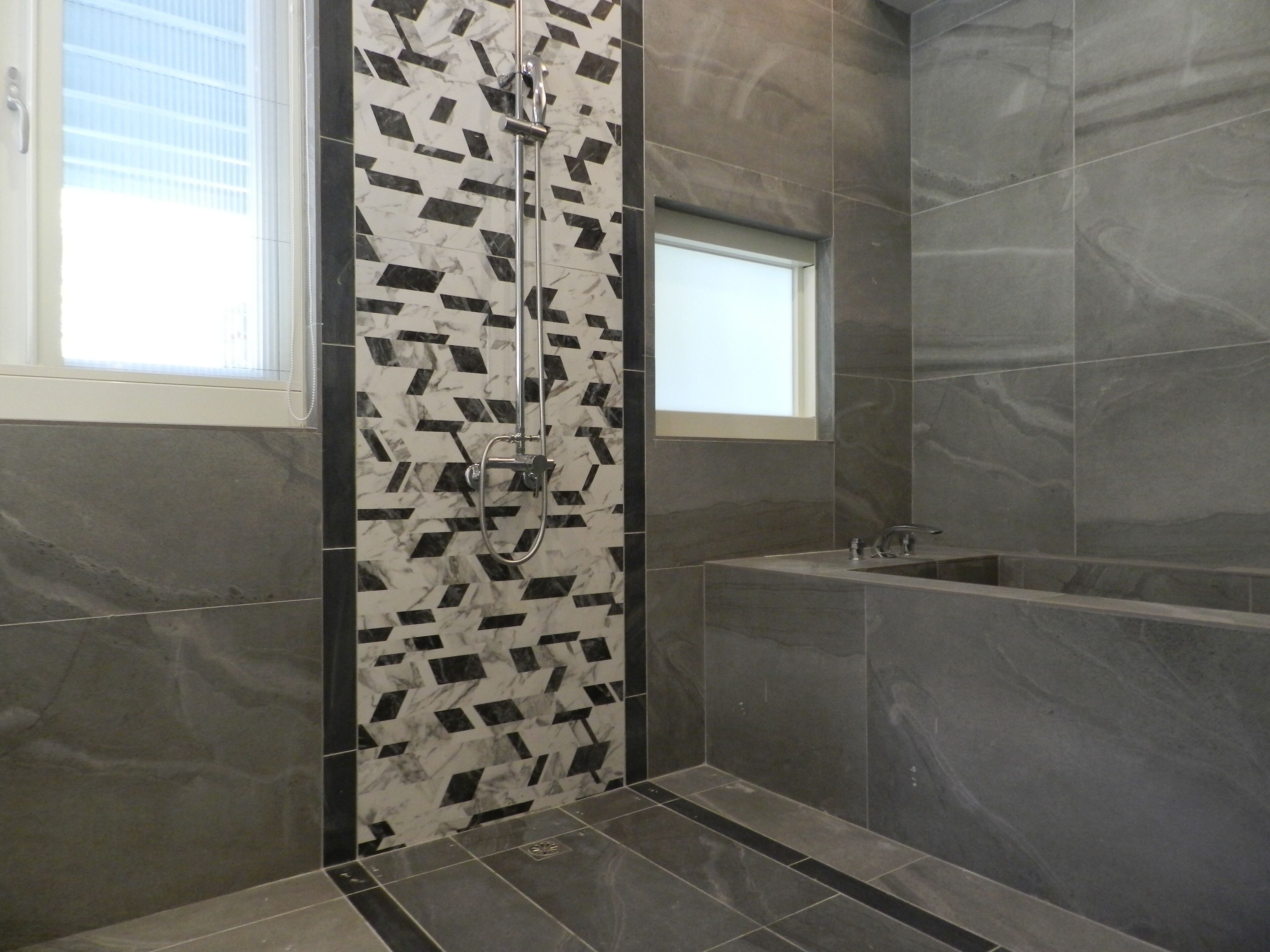 Ein modernes Badezimmer mit Dusche, Badewanne und Fenster.