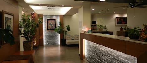 A hotel lobby with a reception desk, seating area, and a stone accent wall.