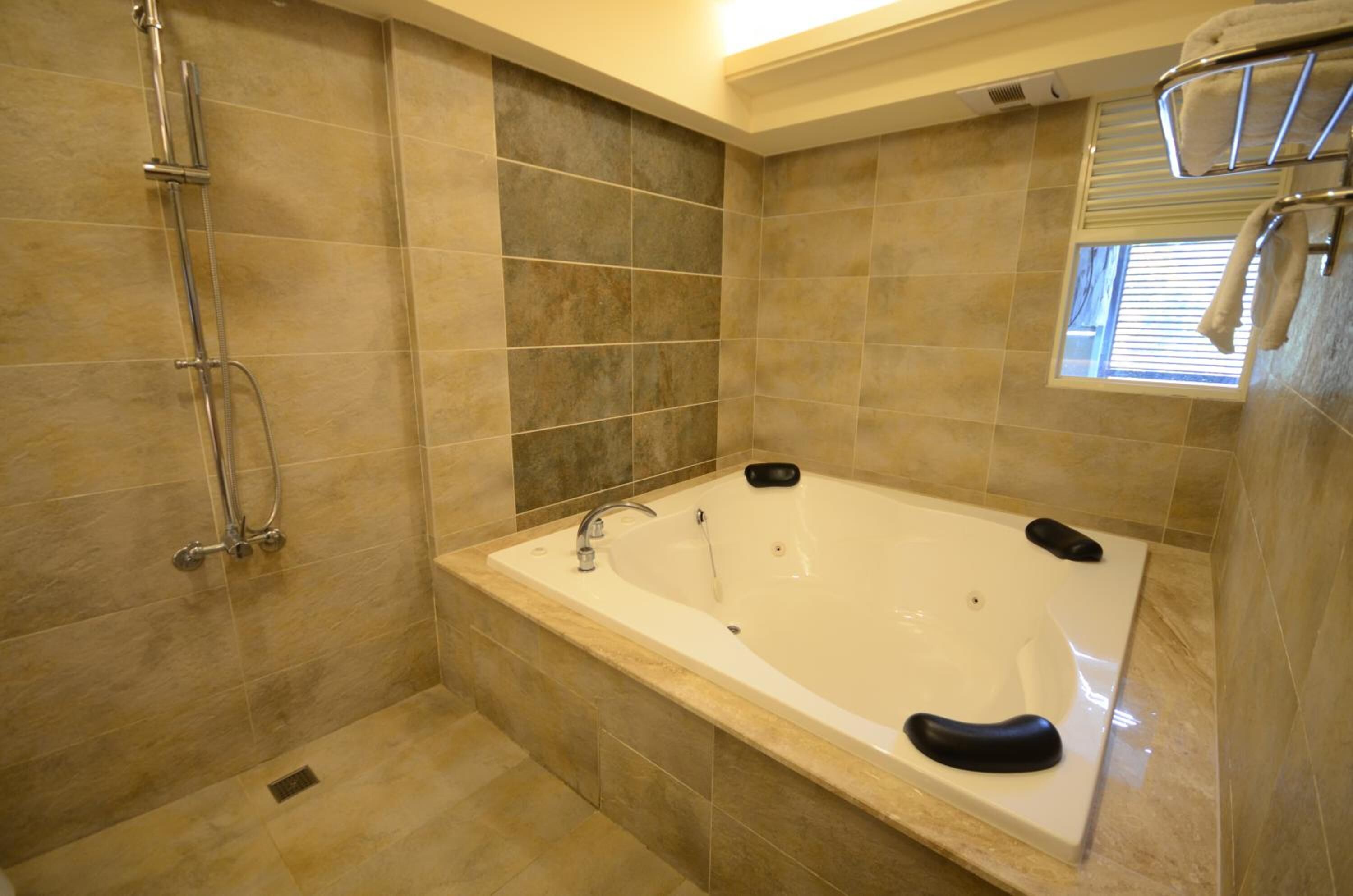 A modern bathroom with a large bathtub, a shower area, and a window providing natural light.