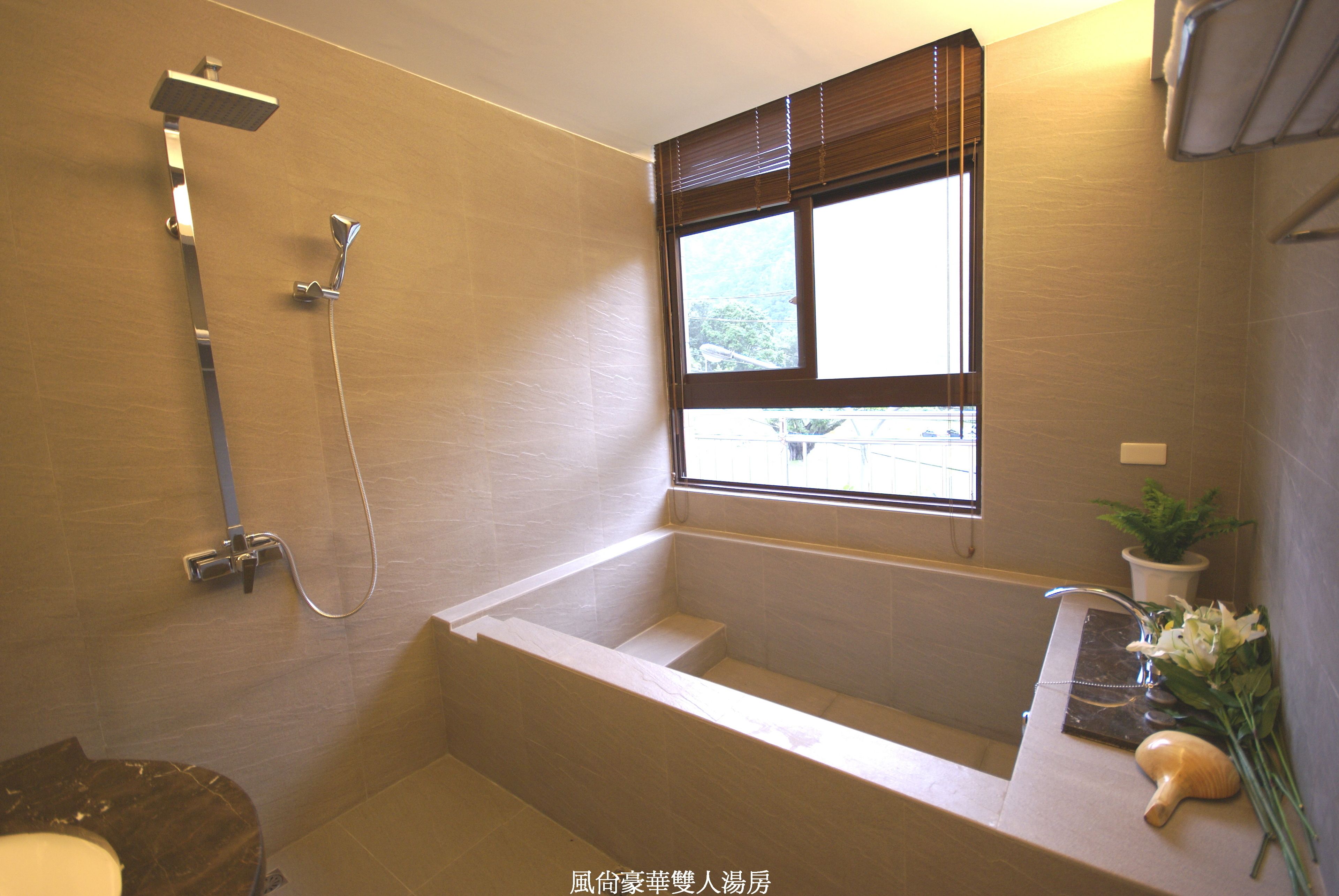 Une salle de bain moderne équipée d’une baignoire, d’une douche et d’une fenêtre laissant entrer la lumière naturelle.