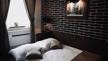 Ein Hotelzimmer mit Backsteinwand, einem Bett mit weißer Bettwäsche und einem gerahmten Bild an der Wand.
