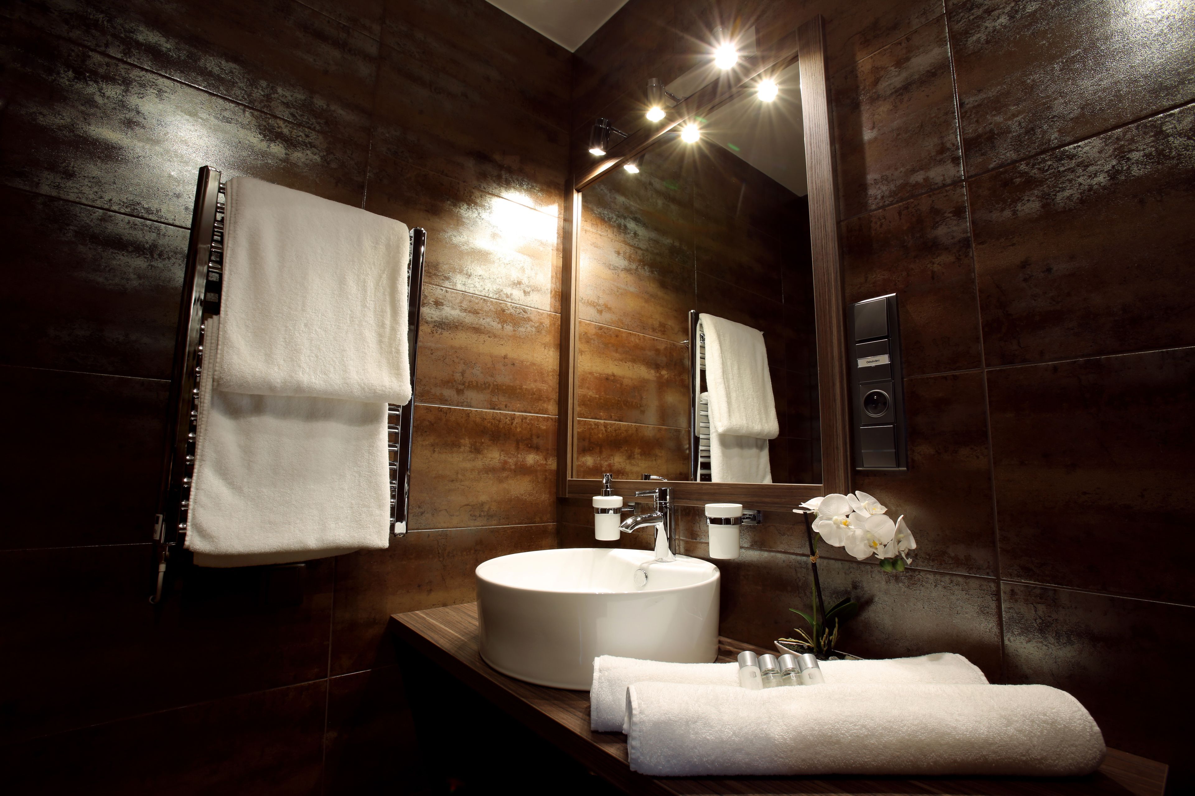 Un baño moderno con un lavamanos grande, un espejo y un perchero para toallas.