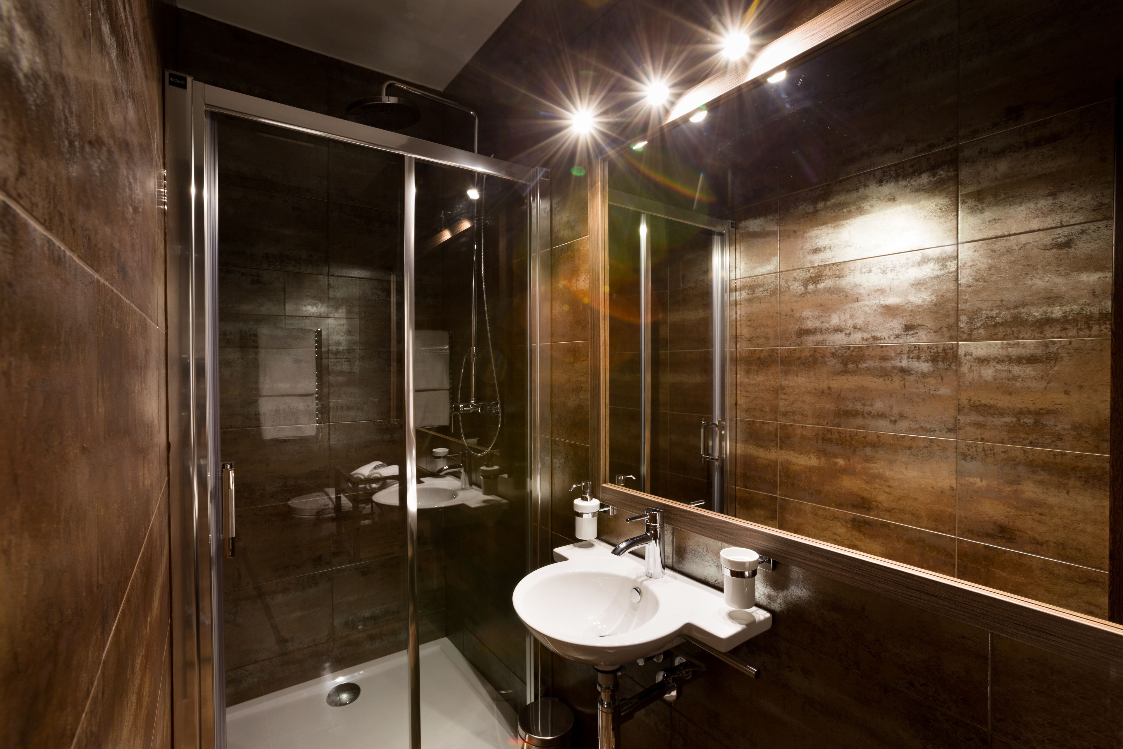 A modern bathroom with a glass shower enclosure, a white sink, and a large mirror.
