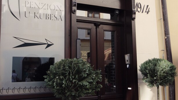 A building facade with a sign reading "PENZION U KUBESA" and a large arrow pointing to the right. There are two potted trees in front of the entrance. - Penzion U Kubesa (Kromeriz)