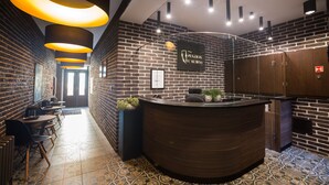 A reception area with a brick wall, a wooden reception desk, and a sign that reads "PENSION L'KUBESA". - Penzion U Kubesa (Kromeriz)