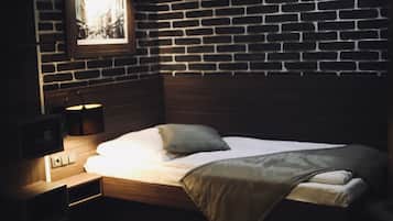 Ein ordentlich bezogenes Bett mit Holz-Kopfteil, einer Nachttischlampe und einem gerahmten Bild an der Wand.