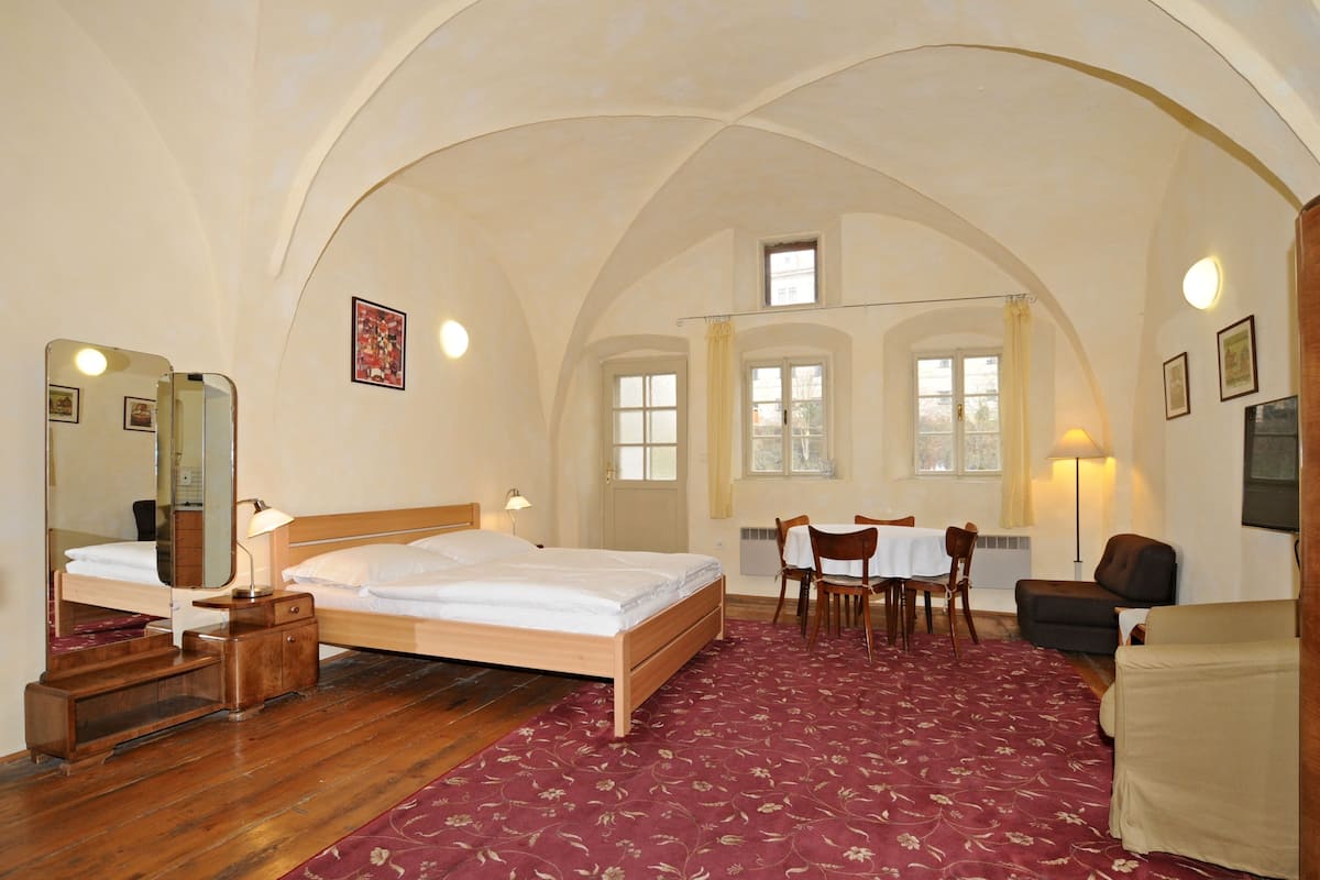 Ein Schlafzimmer mit einem hölzernen Bett, einem Schreibtisch, einem Sessel und einem Sofa.