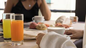 A breakfast setting with two glasses of orange juice, a cup of coffee, and pastries on a table.