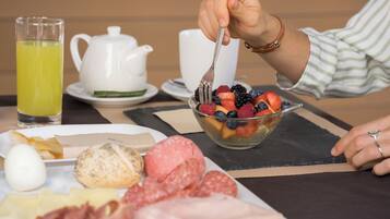 A breakfast setting with a variety of foods including eggs, meats, and a fruit bowl.