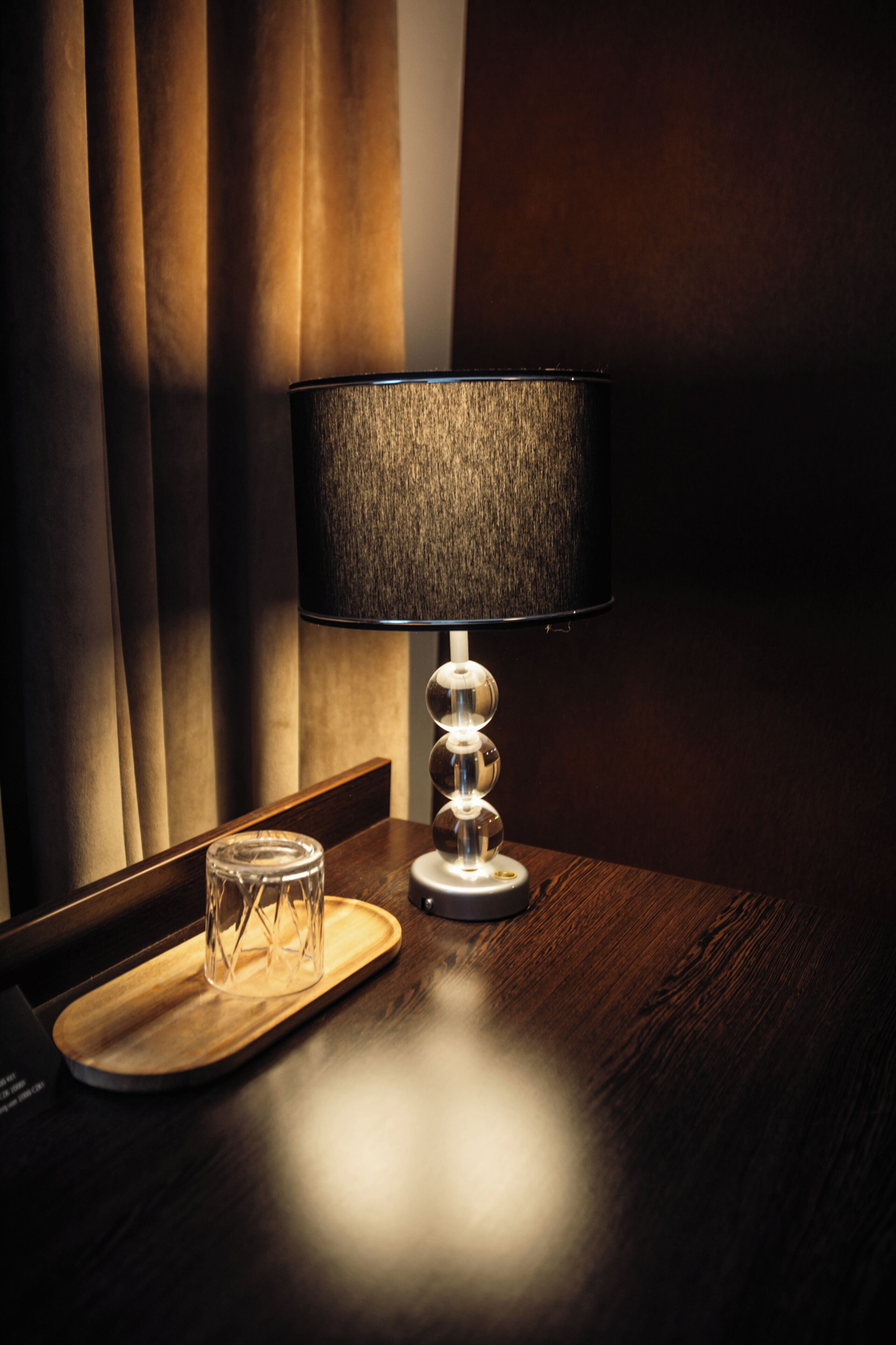 A table with a lamp, a glass container, and a wooden tray.