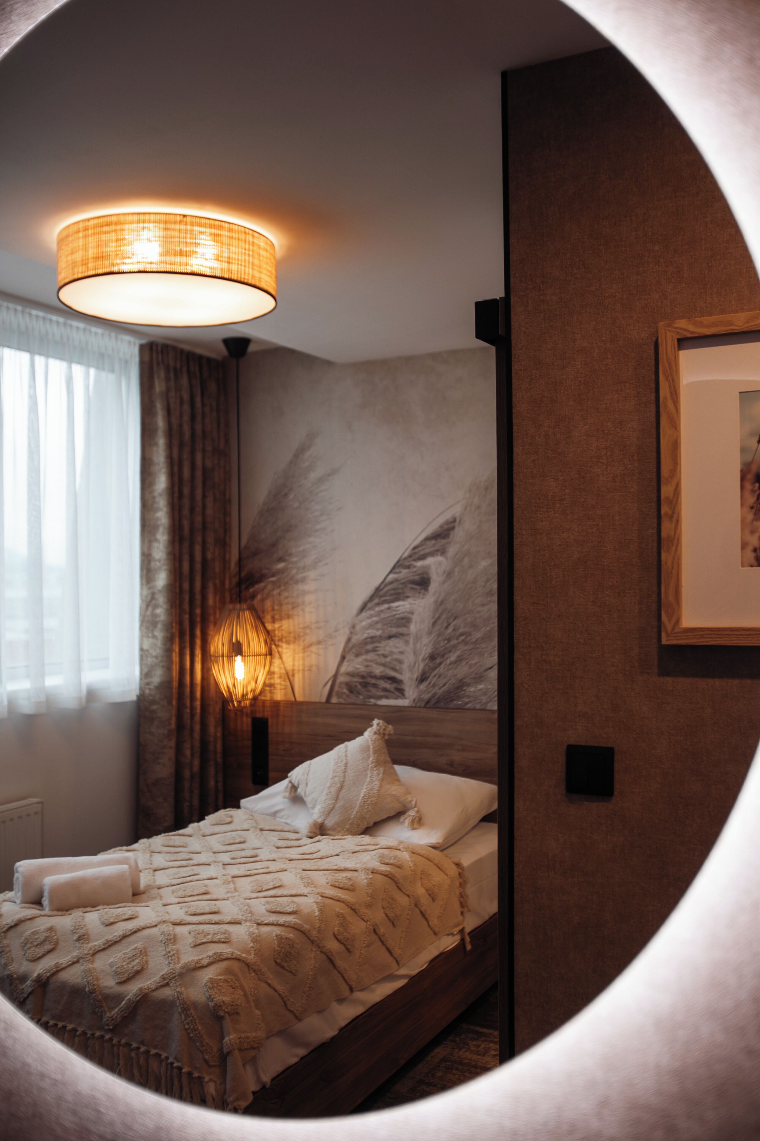 A bedroom with a bed, a wall-mounted lamp, and a framed picture.