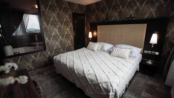 A hotel room with a large bed, a mirror, two bedside lamps, and a view of the outdoors through the window.
