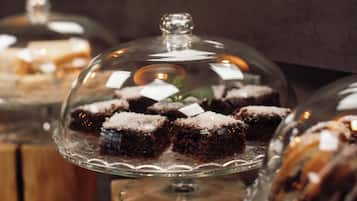 A dessert display with cakes under glass domes on wooden stands.