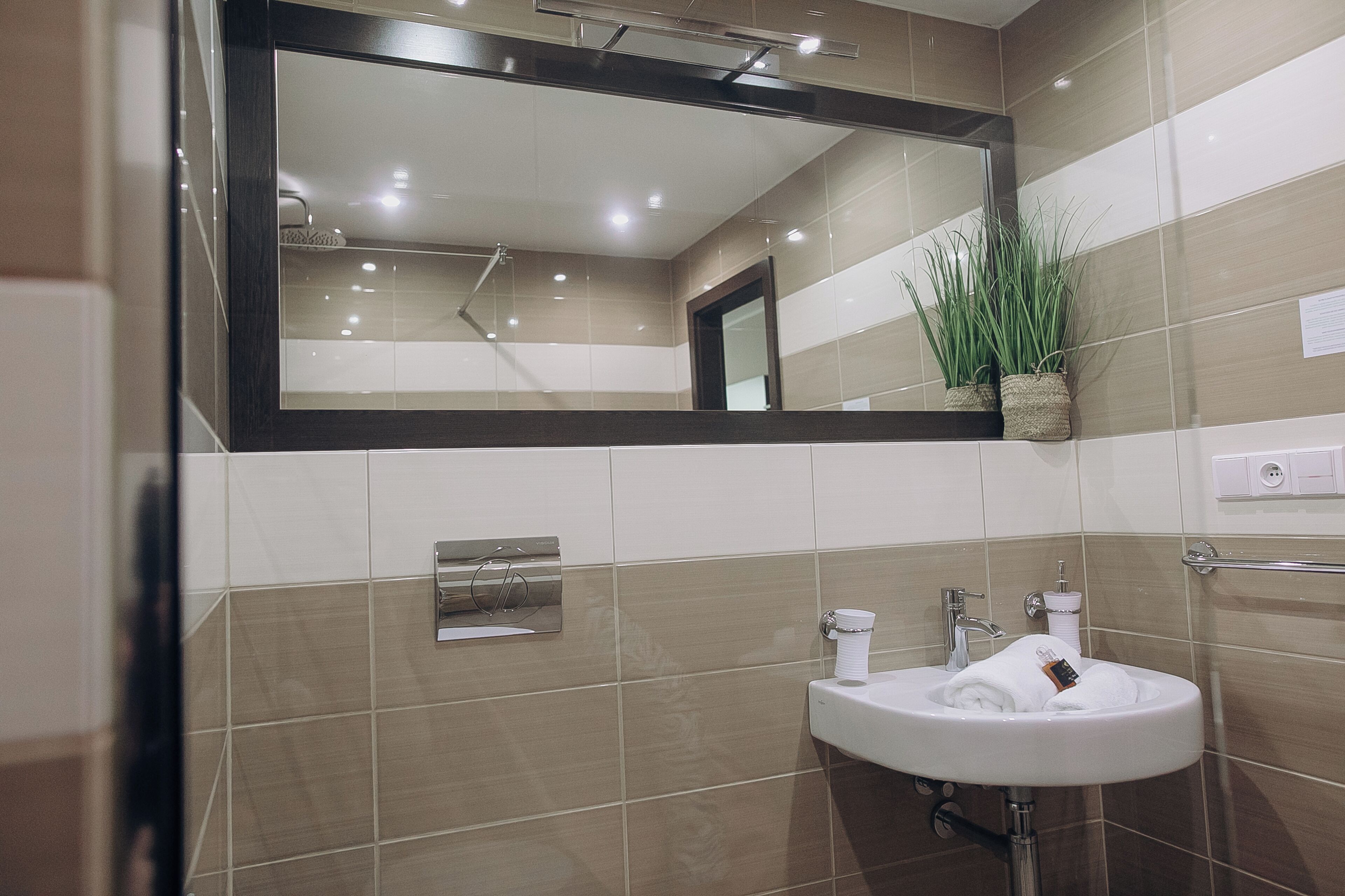 A modern bathroom with a large mirror, a sink, and a towel rack.