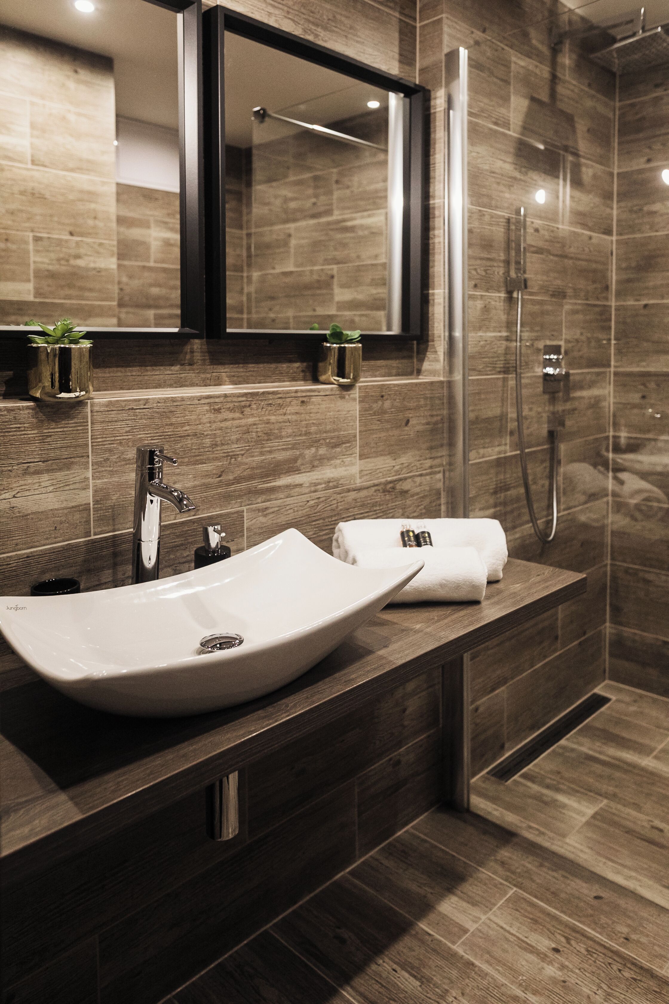 A modern bathroom with a large sink, mirror, and shower.