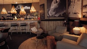 A cozy bar area with wicker chairs, a wooden bar counter, and hanging pendant lights. - Interhotel Tatra (Koprivnice)
