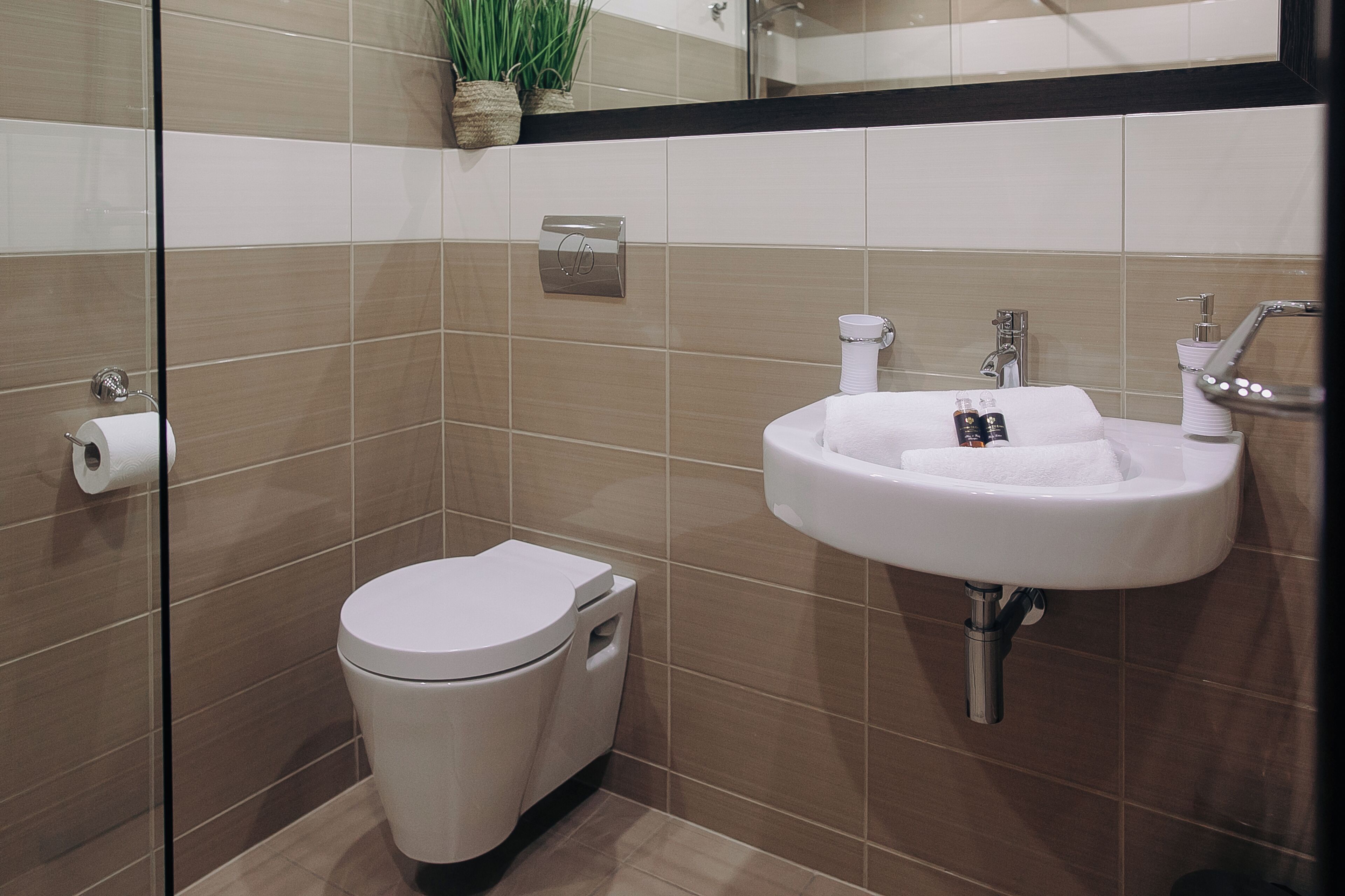 Un baño moderno con inodoro, lavamanos y dispensador de toallas.