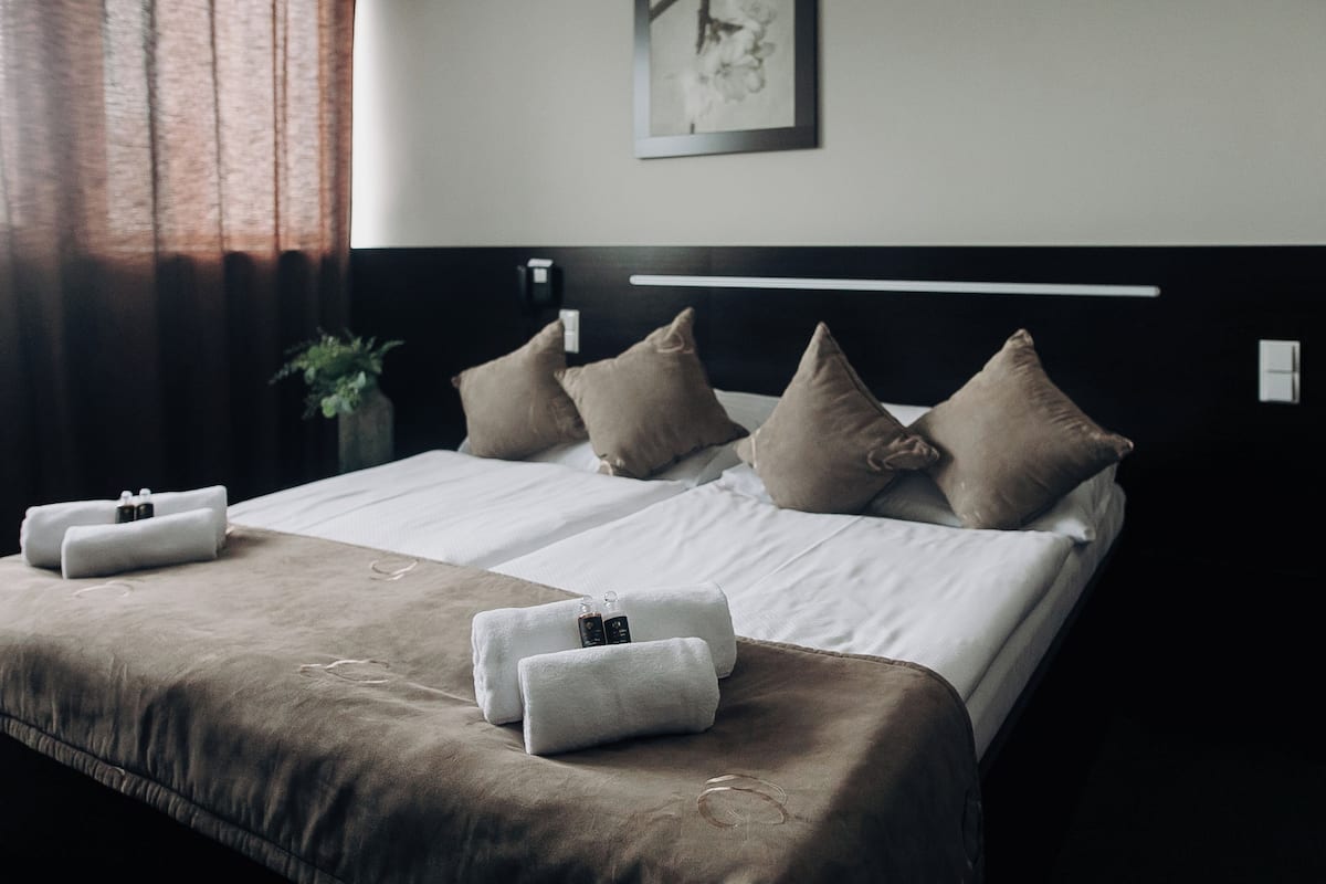 A neatly made bed with a headboard, pillows, and towels.