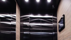 An elevator interior with a wooden panel wall and a black floor with "INTER HOTEL TATRA" text. - Interhotel Tatra (Koprivnice)