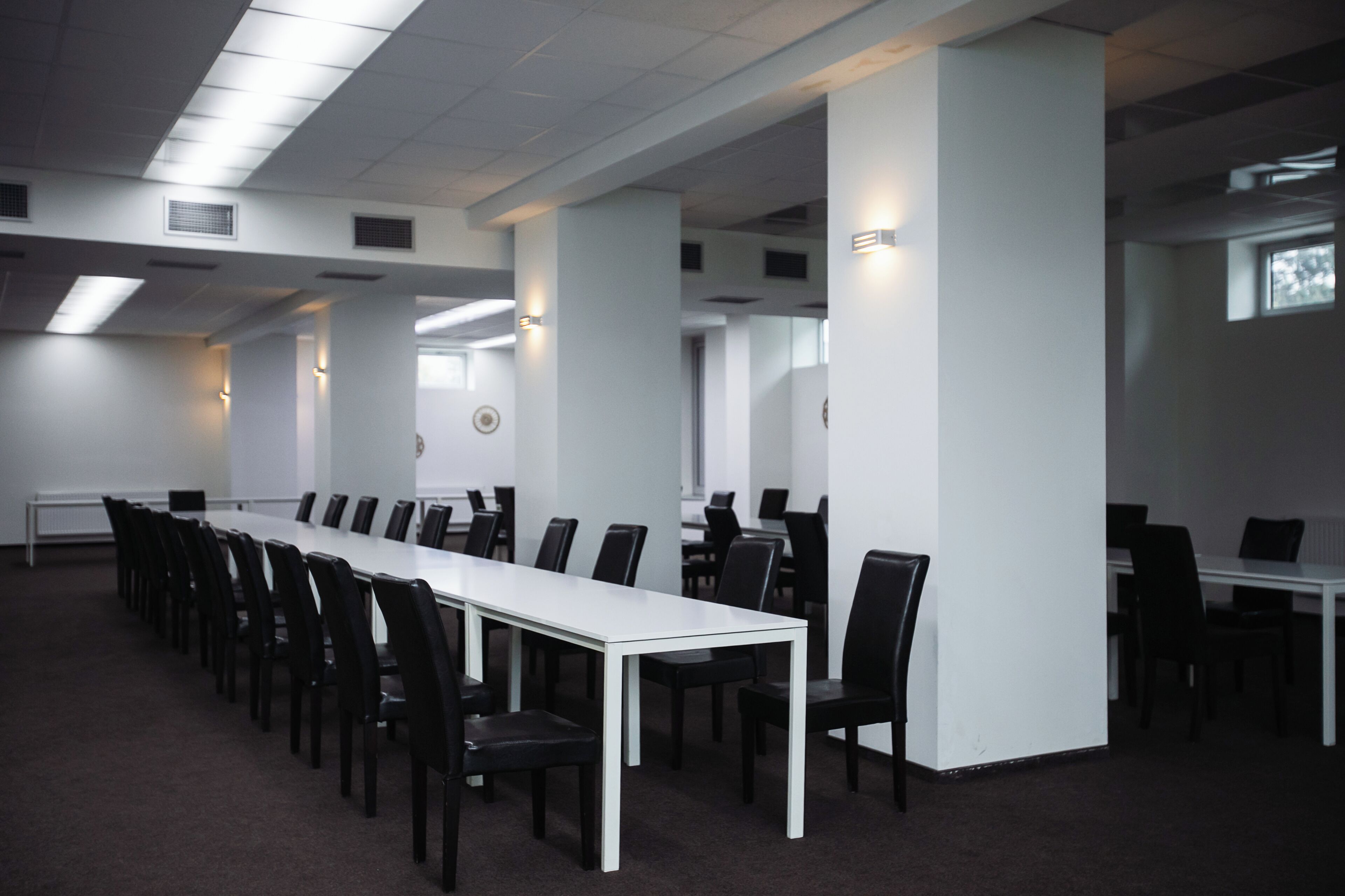 Una sala conferenze con un lungo tavolo e sedie, pareti bianche e luci a soffitto.
