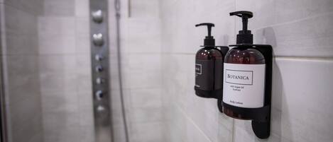 A bathroom with a shower and two body lotion dispensers labeled 'BOTANICA with Argan Oil EcoPure Body Lotion'.