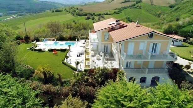 A large two-story house with a swimming pool and a well-maintained lawn.