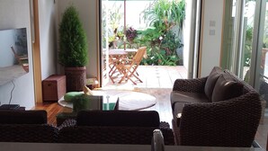 A kitchen with a sink, a dining area with a table and chairs, and a view of the outdoor patio with plants and a ceiling fan. - Green House (Urasoe)