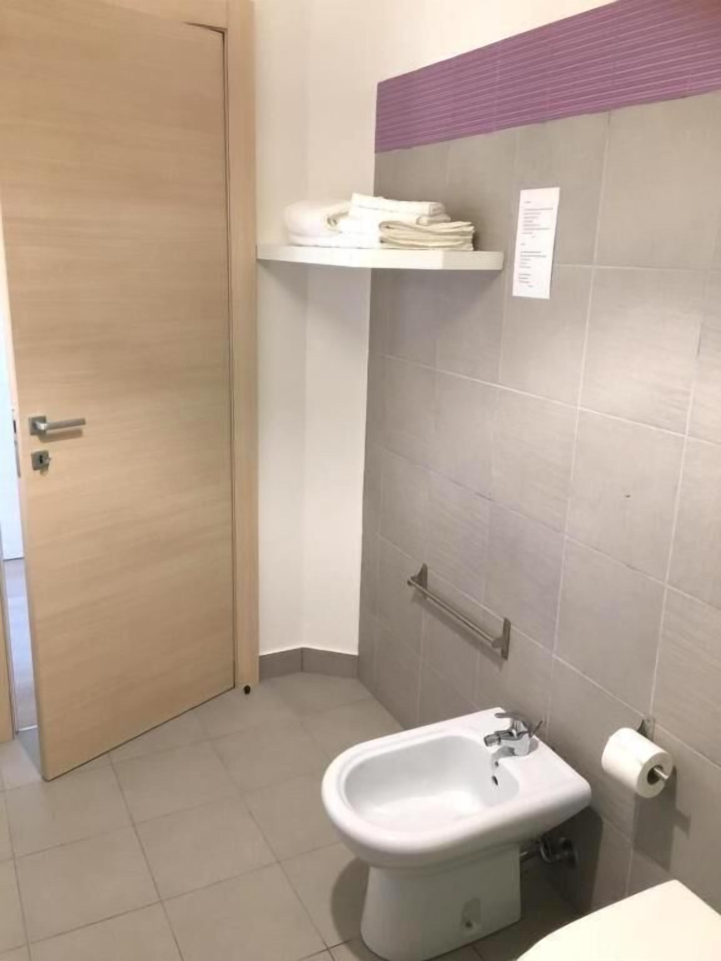 Casa de banho com sanita, bidé e porta-toalhas.