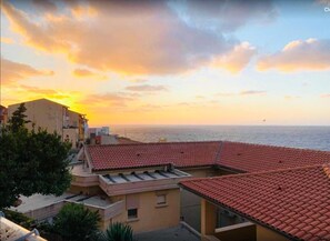 A coastal building with red-tiled roofs and a view of the sea at sunset. - Blu Bed & Breakfast (Castelsardo)