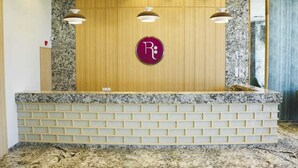 A reception desk with a marble top and a wooden panel backdrop. - Regenta Central Harsha Vapi (Pardi)