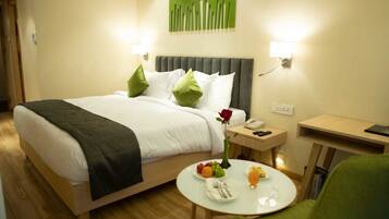 Una habitación de hotel con cama, mesita de noche y una pequeña mesa redonda con elementos para el desayuno.